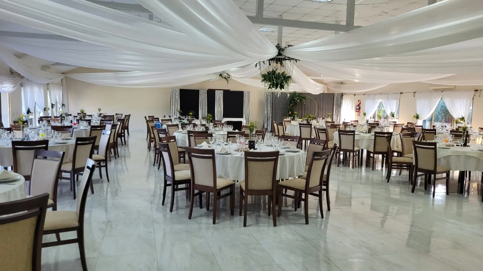 Salón con telas en el techo y mesas redondas